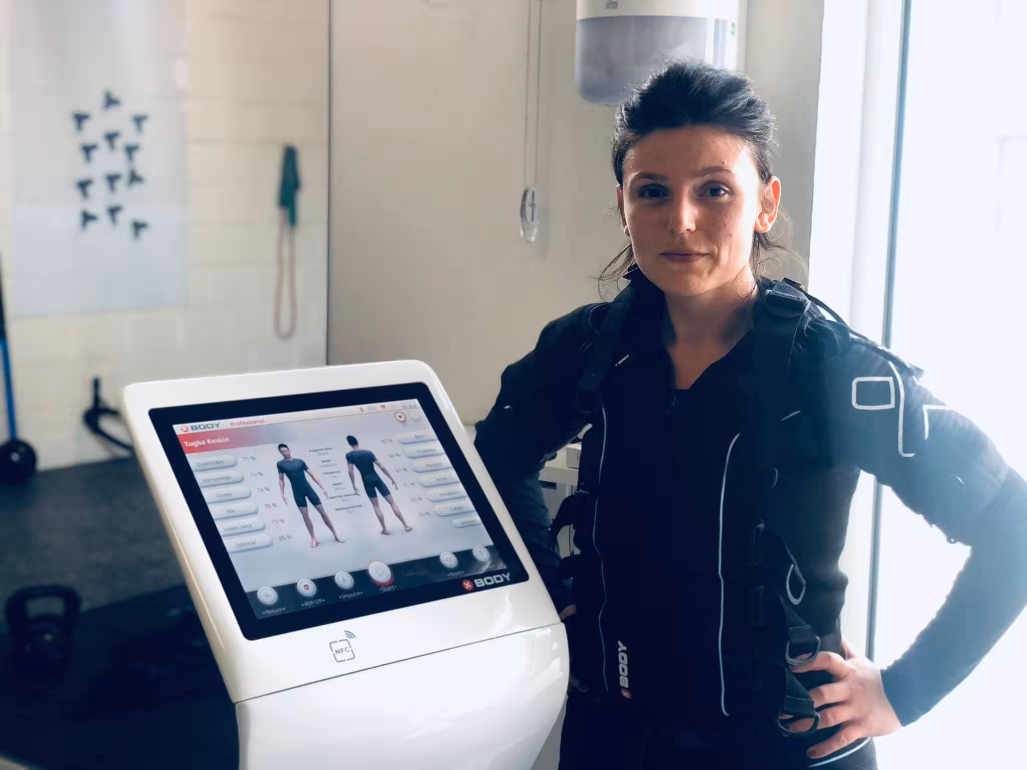 Vrouw in Xbody EMS pak naast het toestel